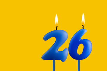 Blue birthday candle on yellow background - Number 26