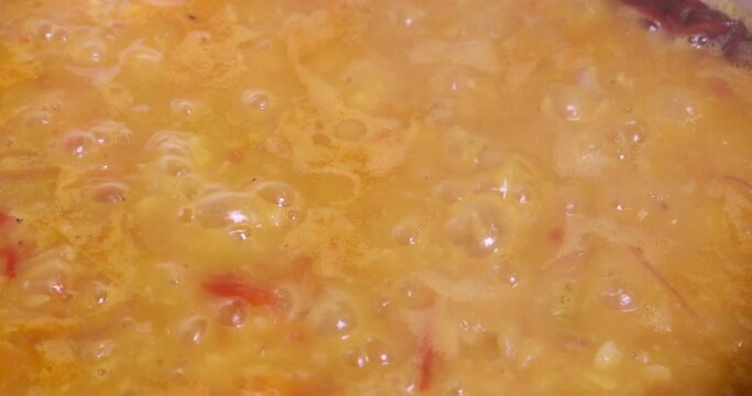 Adding boiling dal lentil into bagar tadka with deep fry tomato onion garlic cumin red dry chilli spice stair cooking dal ghotni whisk 