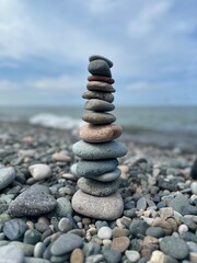 Balanced pebbles pyramid on the beach on sunny day and clear sky at sunset	
