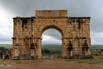 view of the ruins of the Triumphal Arch and city gate in the ancient Roman Berber city of Volubilis in Morocco