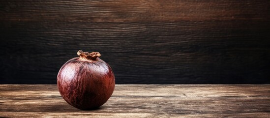 An image of a mangosteen fruit on a brown wooden table with a rustic appearance and aged aesthetics offers a unique copy space image