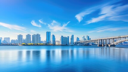 Fototapeta premium the picturesque cityscape and bridge on a sunlit day, where tranquil waters reflect the clear blue sky dotted with wispy clouds.