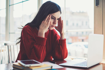 Tired puzzled woman using  modern laptop computer for watching bad tutorials indoors, concentrated...