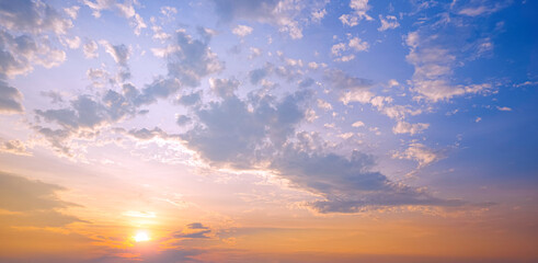 Fototapeta premium Sunset sky in the evening with yellow sunlight and clouds on blue majestic sky background, Idyllic natural sunrise sky in panoramic view
