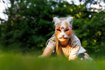 Cute young little kid girl wear cat furry mask enjoy have fun playing outdoors in forest street...