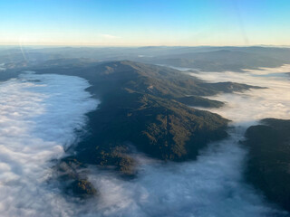 Aerial view of a mountain range surrounded by fog and clouds