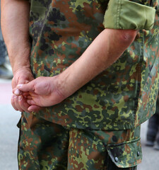 Military guard in camouflage uniform at barracks with hands behind back