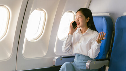 Asian woman looking at phone while sitting on airplane Technology female travelers using mobile...