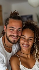 Young couple smiling at camera embracing with one person wearing white top and the other with a black choker.