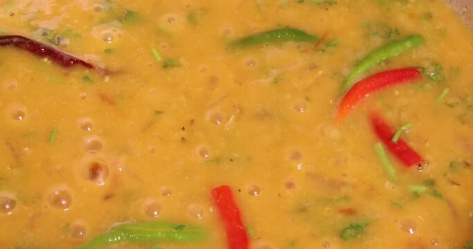 Adding boiling dal lentil into bagar tadka with deep fry tomato onion garlic cumin red dry chilli spice stair cooking dal ghotni whisk 