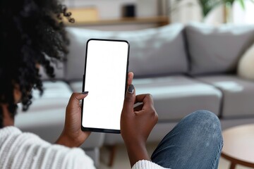Woman using a Smart Phone with White Screen. Back view of Girl wear Jeans sitting in Living room using Mobile Phone Chroma Key Screen. African American Female is watching, looking at WhiteScreen Phone