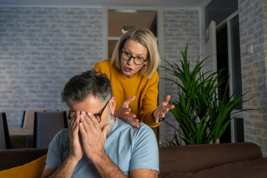 Family quarrel, woman quarrels and yells at the loser's husband, couple at home sitting in the dining room at the table. Couple fighting in the morning. woman screaming to her man. - Powered by Adobe
