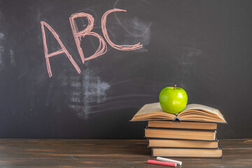 Study books on wooden desk in front of blackboard with English litters. Back to school concept.