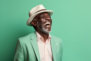 Portrait of a glad afro-american man in his 50s laughing on pastel green background