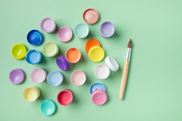 Naklejka premium Pastel colors gouache in jars on table top view. Creative hobby painting concept.