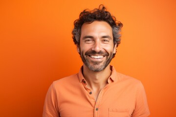 Portrait of a glad man in his 30s smiling at the camera over pastel orange background