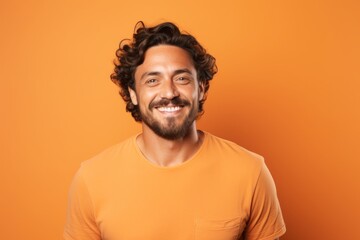 Obraz premium Portrait of a cheerful man in his 30s smiling at the camera in pastel orange background