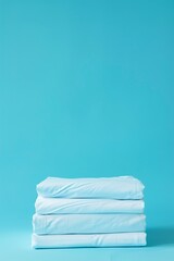 Stack of clean bed sheets on blue background. Space