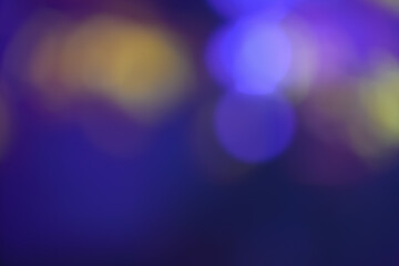Abstract image with soft undefined shapes of blue and yellow colors and blurry circle lights like those of a music concert stage. Dark background.