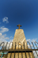 sillhoette of stone grave cross against the background of a blue evening sky with clouds