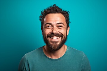 Fototapeta premium Portrait of a grinning man in his 30s smiling at the camera isolated on pastel teal background