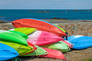 Colorful sea kayaks on the shore in Cobo bay, Guernsey, CHannel Islands - Powered by Adobe