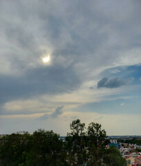 Beautiful blue sky background,  sun hiding behind clouds over the city, nature photography