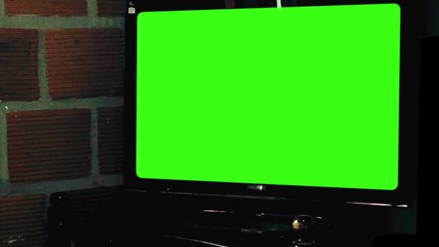 Computer Monitor with Green Screen Against Brick Wall in A Shanty House. Close Up.