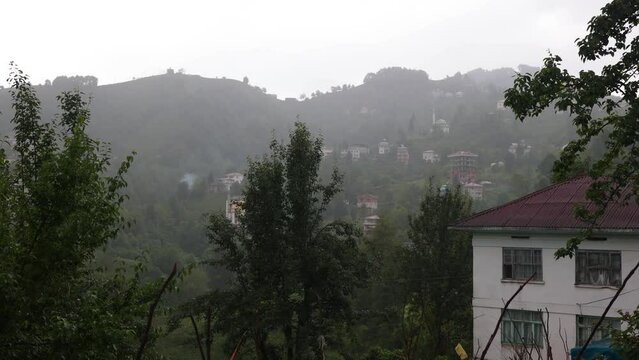 Rainy day in the mountains in Turkey. Rain and fog, mountains and houses, green plants and rain.