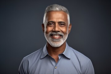 Obraz premium Portrait of a grinning indian man in his 50s with arms crossed isolated on pastel gray background
