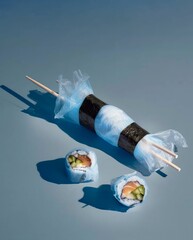Sushi rolls with chopsticks on a blue background, top view.
