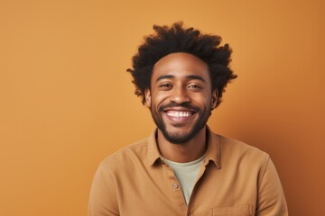 Obraz premium Portrait of a merry afro-american man in his 30s smiling at the camera on pastel brown background