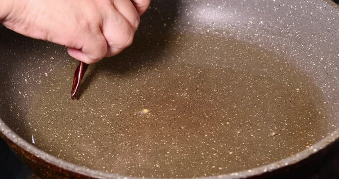 saut&eacute; fry toss whole cumin dry red chilli in hot oil preparation cooking on frying pan