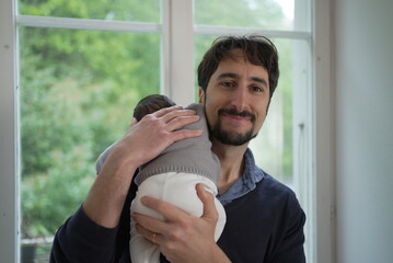 A father beams with joy as he cradles his newborn baby, highlighting a heartwarming moment of love...