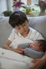An affectionate kiss from an older brother to his newborn sibling, capturing a sweet and loving...