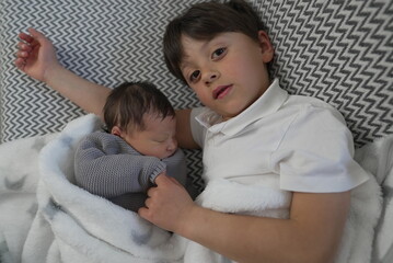 An older brother snuggles close with his newborn sibling, highlighting a sweet and serene moment of...