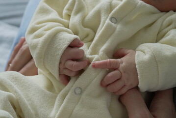 A close-up of a peacefully sleeping newborn baby dressed in a soft yellow onesie, capturing the...