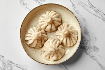 Savory khinkali dumplings sprinkled with black pepper on ceramic bowl