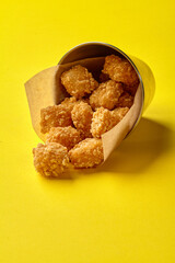Crispy fried chicken nuggets spilling from metal bucket on yellow