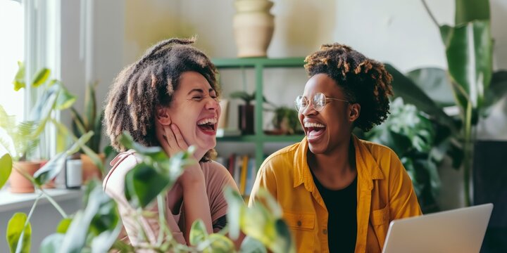 Two friends enjoying a funny moment together while looking at a laptop at home