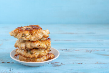 Chicken schnitzels on miniature plate over blue wooden background with copy space.
