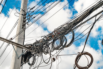 Electric pole and wire with blue sky, wires tangled, cable electricity or telephone line in city of...