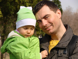 Portrait of little adorable serious girl and smiling father in spring outdoors