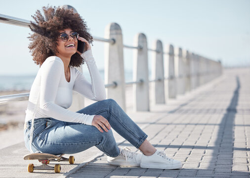 Happy, laugh and black woman by ocean with skateboard for weekend, holiday and vacation in trendy style. Fashion, promenade and person skateboarding for activity, freedom and adventure by seaside