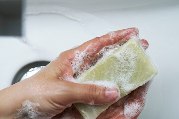 Fototapeta premium The process of washing hands with natural soap over the sink.
