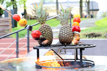 Pineapple,green pepper,tomato, lemon and onion they are placed on a cast iron grill to be cooked.