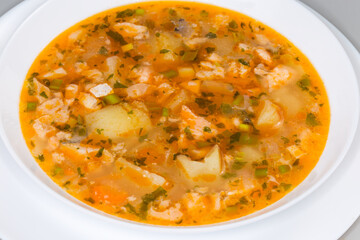 Clear salmon soup in white bowl, close-up