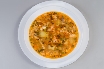 Portion of clear salmon soup on gray background, top view