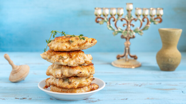 Chicken fritters or latkes for Jewish holiday Hanukkah on the background of traditional decorations.