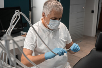 A dentist in medical gloves and mask is treating a patients teeth